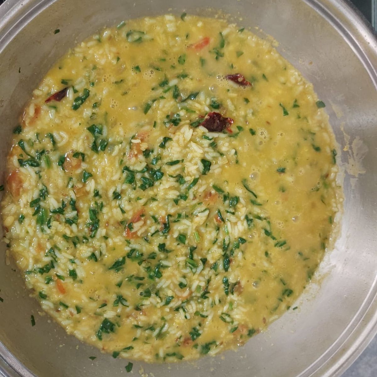 spinach moong dal khichdi in a wide steel pan.