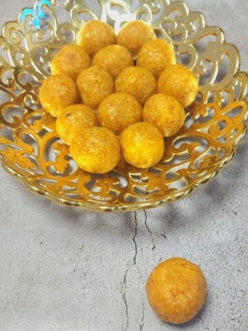 golden bowl of apricot bliss balls placed on grey granite.