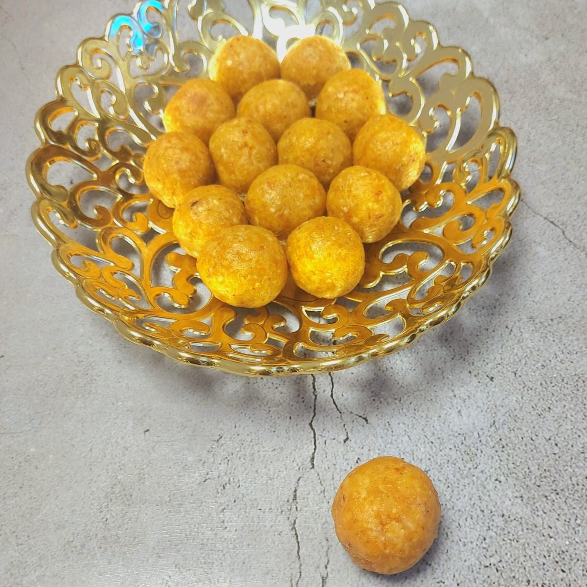 golden bowl of apricot bliss balls placed on grey granite.