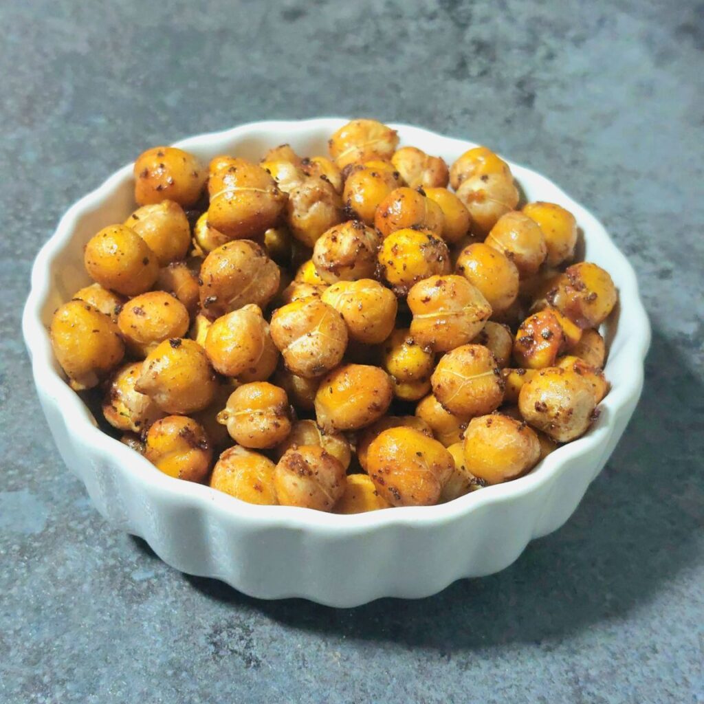 white bowl of maple cinnamon roasted chickpeas placed on grey granite.