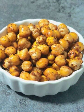 white bowl of maple cinnamon roasted chickpeas placed on grey granite.