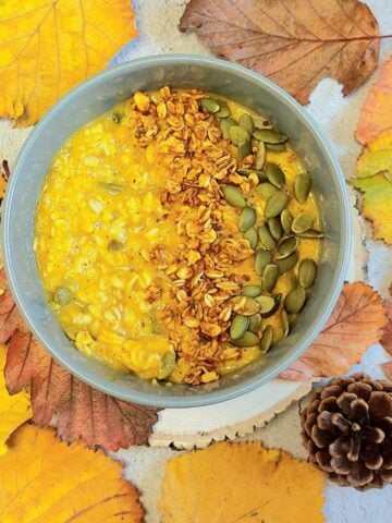 bowl of pumpkin oatmeal porridge placed with autumn leaves.