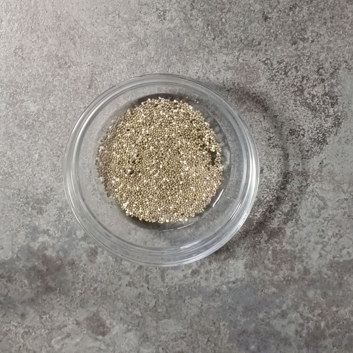 glass bowl with soaked chia seeds placed on black granite.