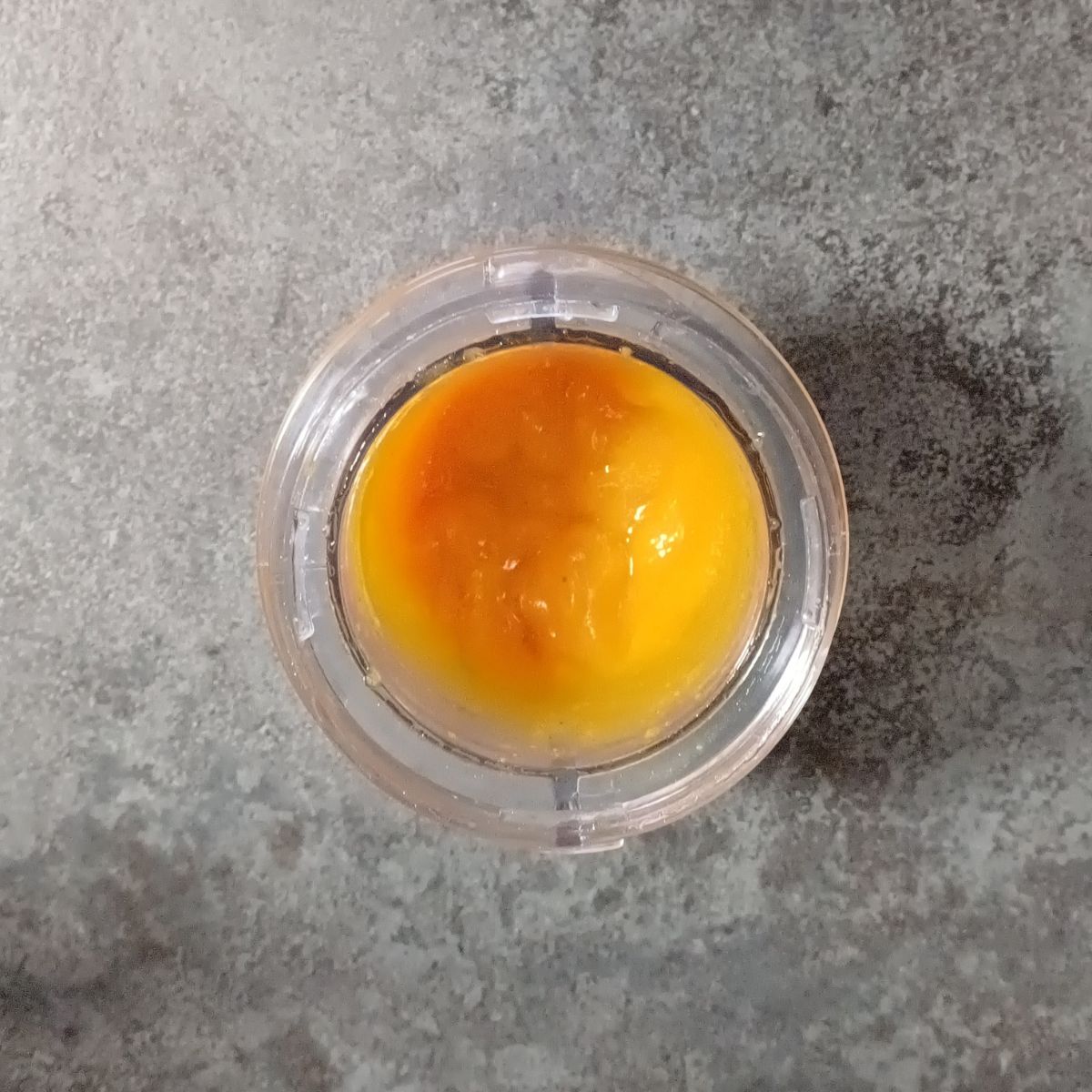 blender jar with persimmon puree placed on black granite.