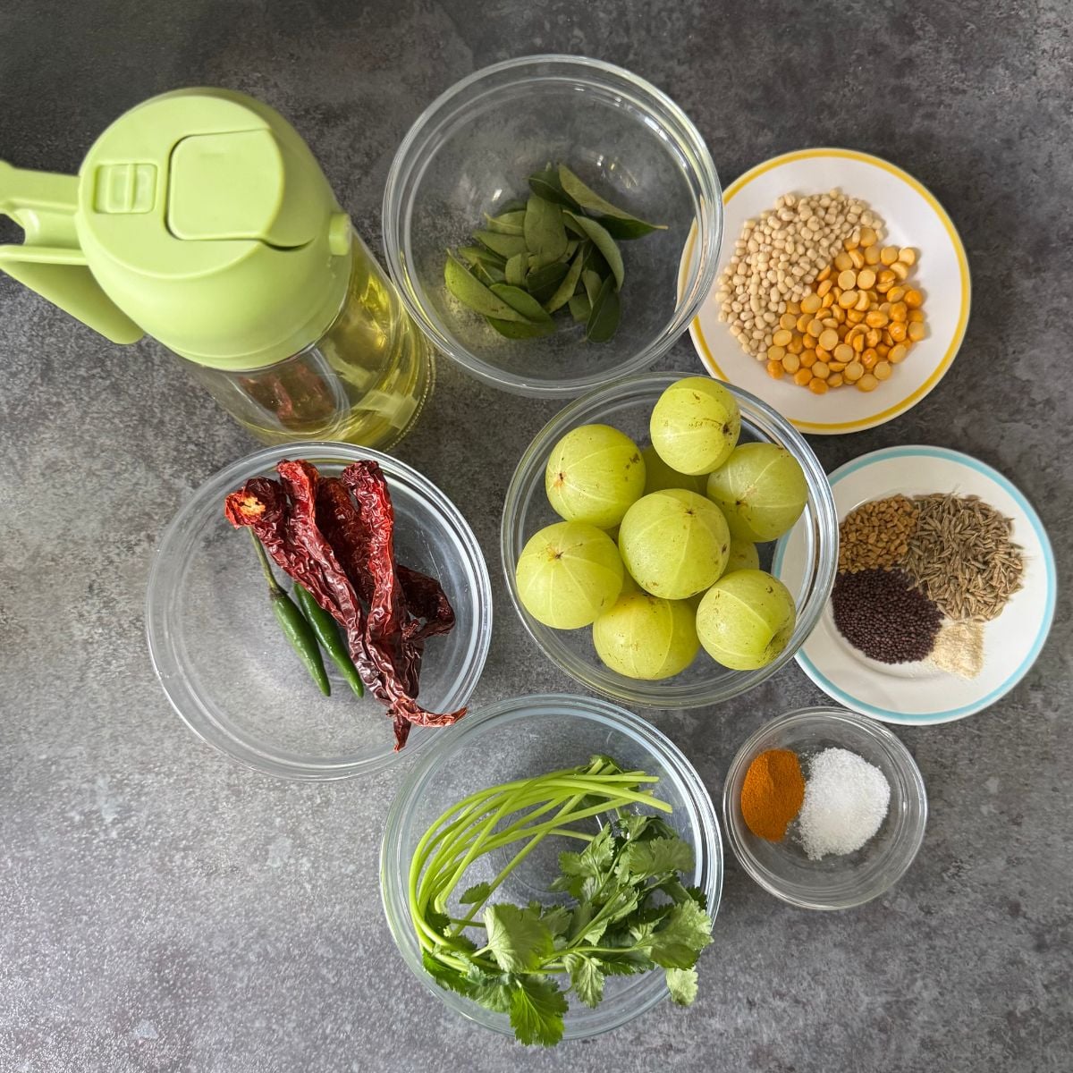 Indian gooseberries, spices, lentils and oil placed on grey granite.