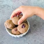 child picking up 4 ingredient banana oatmeal energy ball from a bowl.