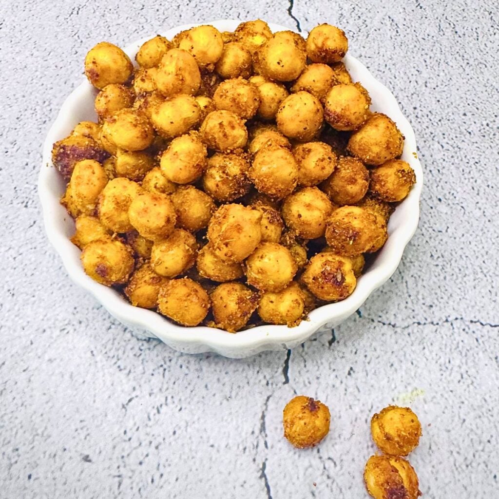 close up image of crunchy spicy oven roasted chickpeas in a white bowl.