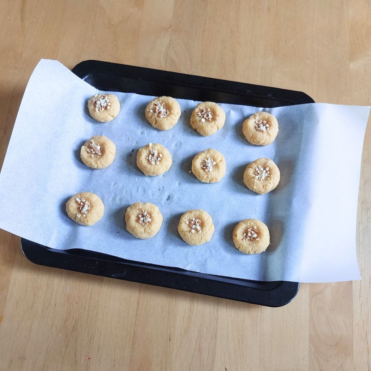 orange almond cookies arranged on a lined baking sheet ready to be baked. 