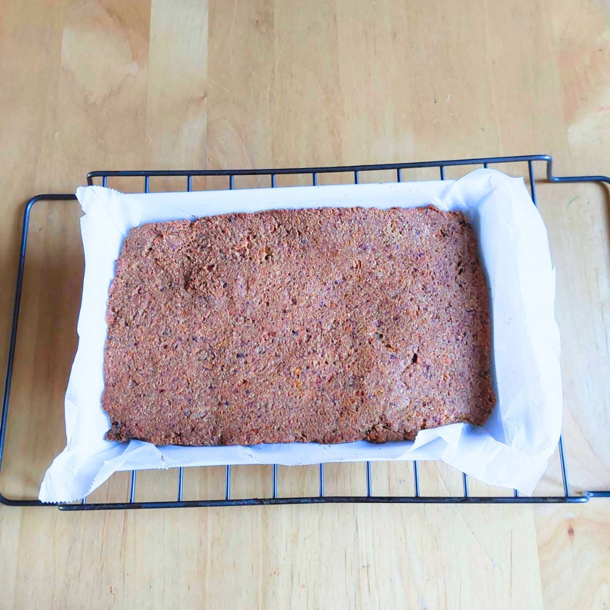 baked toddler friendly carrot date oat bar in a baking dish placed on wire rack.