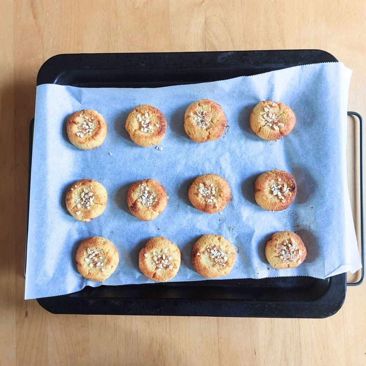 baked 3 ingredient kid friendly orange almond cookies in a lined baking sheet