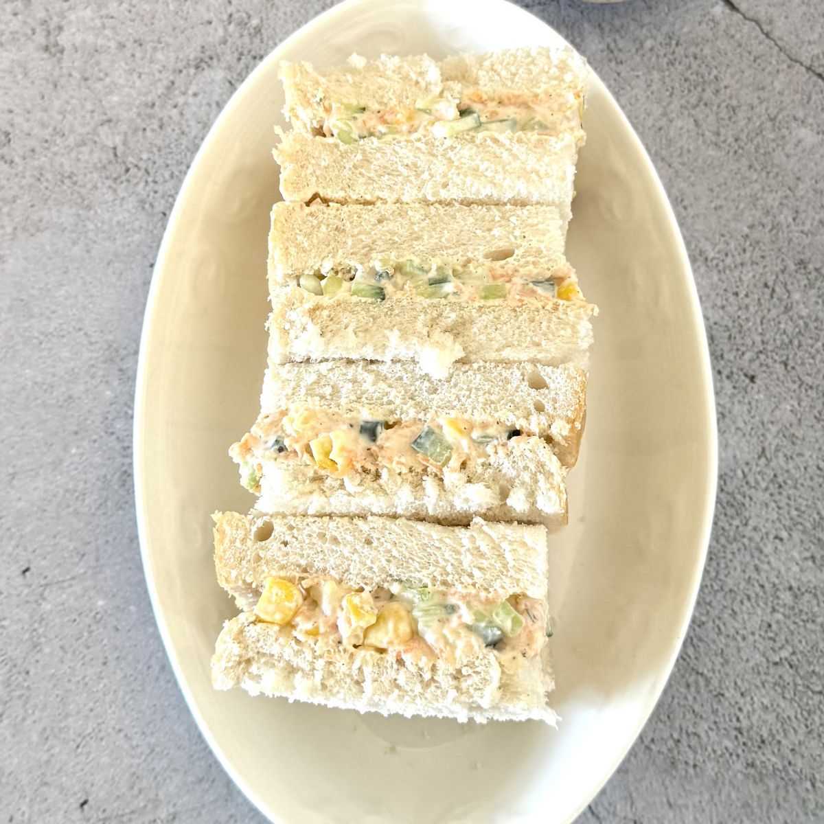 sandwich squares arranged on white plate placed on grey granite.