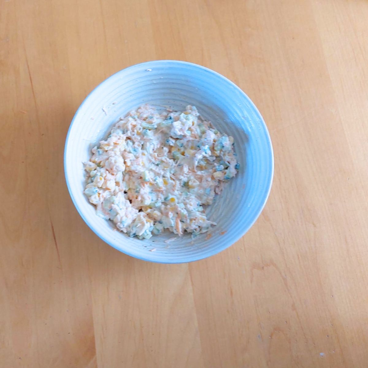 bowl of vegetable cheese spread placed on wooden table.