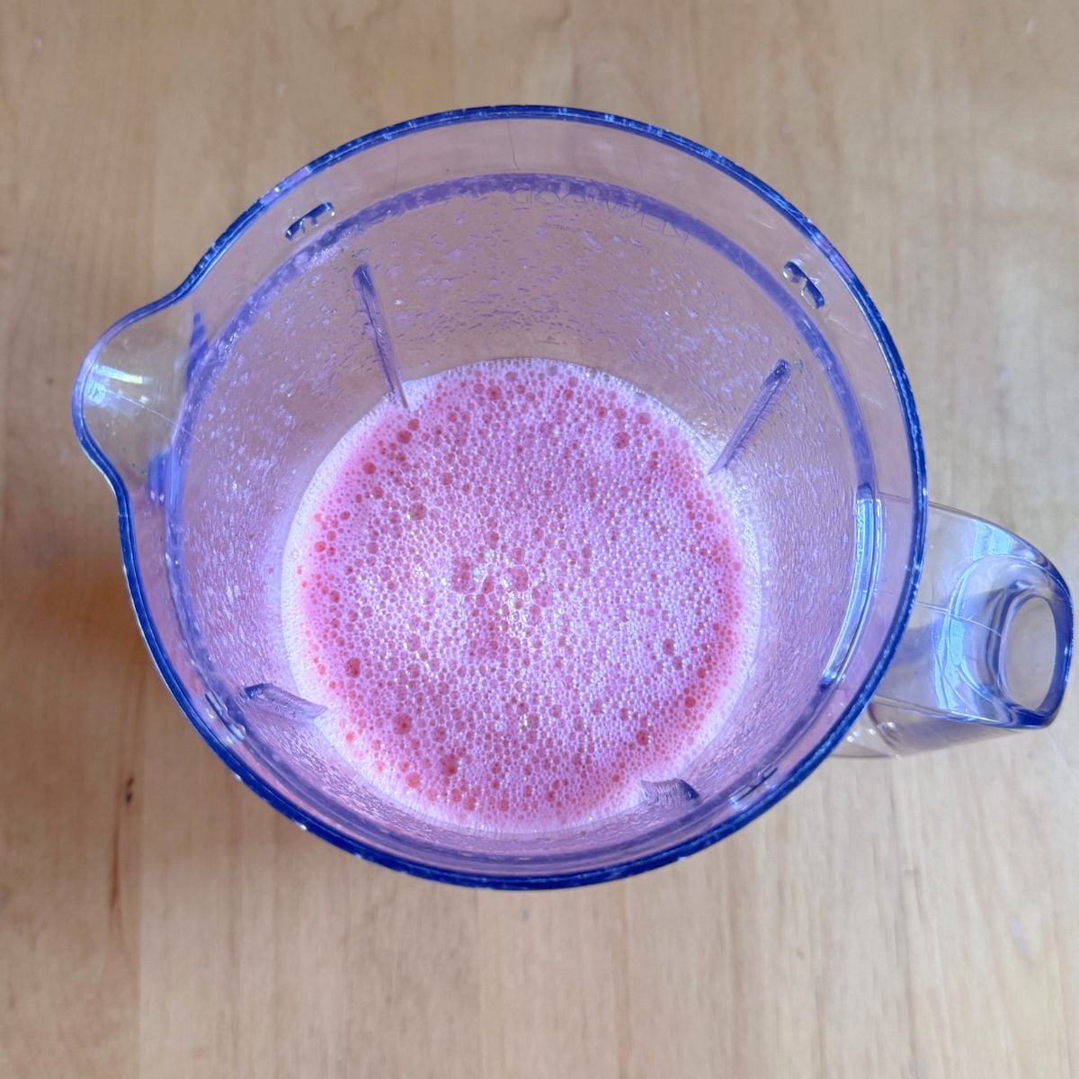 top view of blender with watermelon juice placed on wooden table.