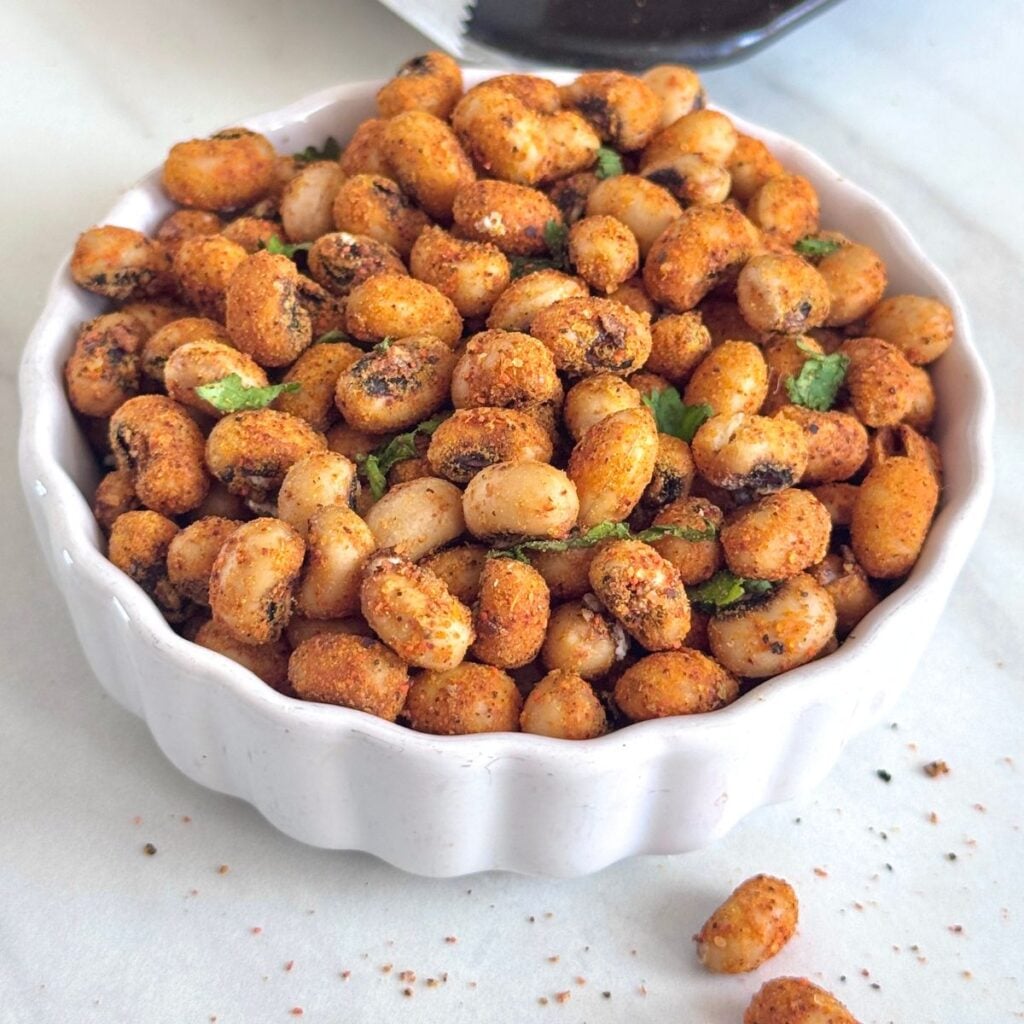 white bowl filled with spicy crispy roasted black eyed peas placed on marble.