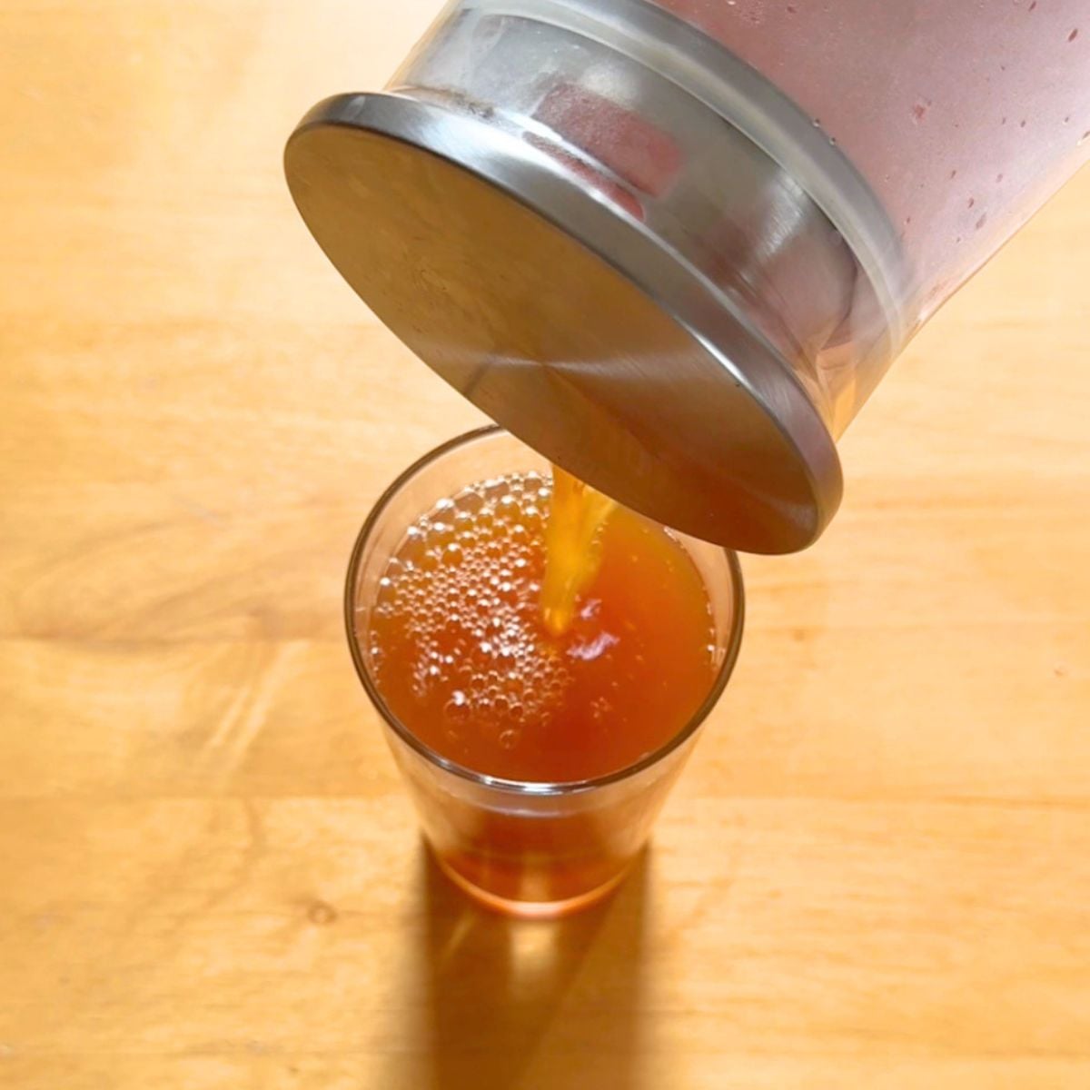 pouring lemon ginger tea from a jug into a glass