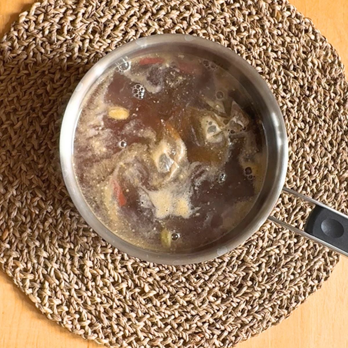 top view of a steel teapot of brewed spiced iced lemon ginger tea placed on placemat.