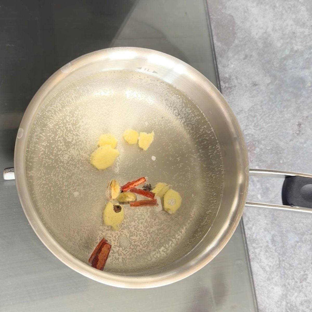 spices and ginger simmering in of water. a steel pot