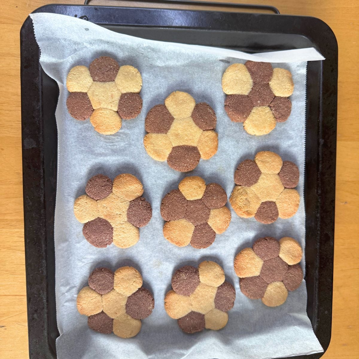 baked vanilla chocolate almond cookieson lined baking tray on wooden table.