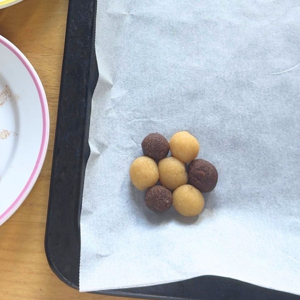 cream and chocolate coloured balls arranged in circular shape on lined baking tray