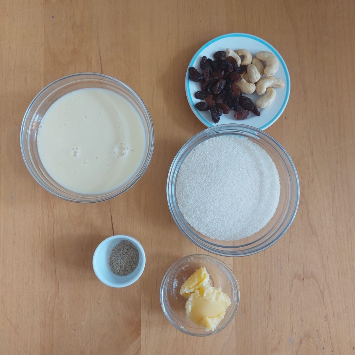 ingredients to make condensed milk rava laddu placed on wooden table.