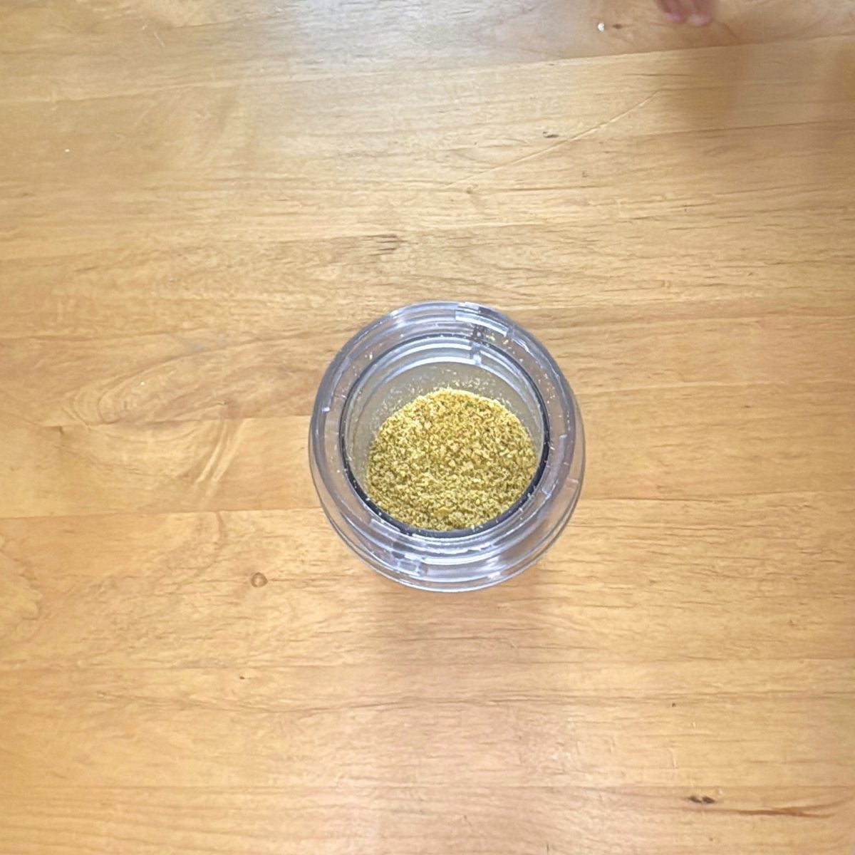 blender jar of ground pistachios on wooden table.