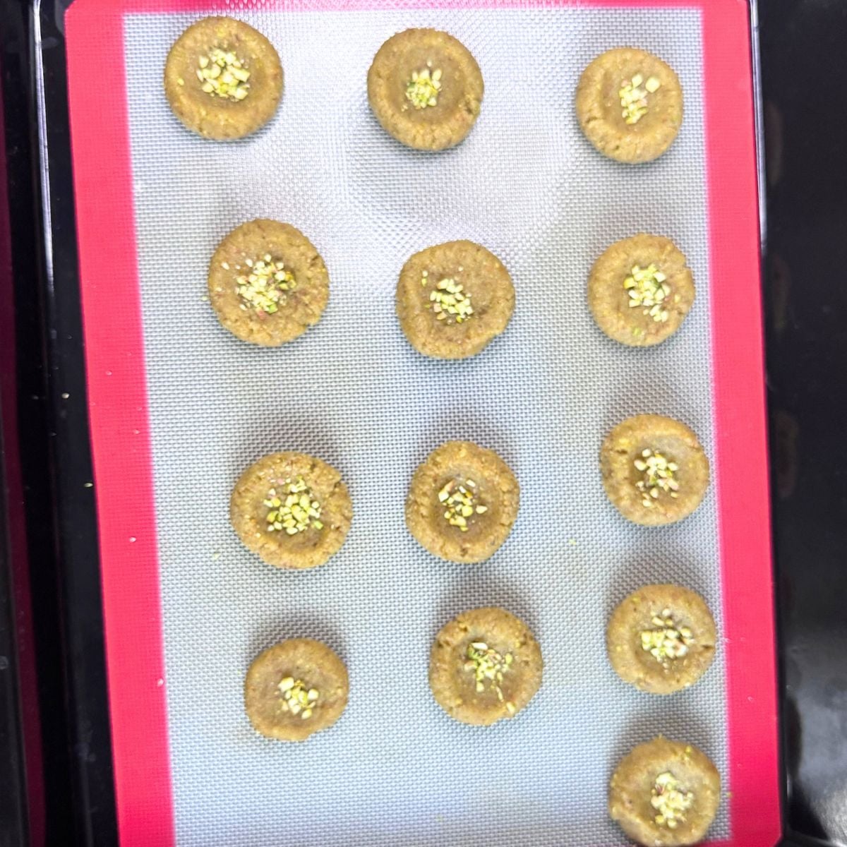 almond flour pistachio cookies on lined baking tray ready to be baked.