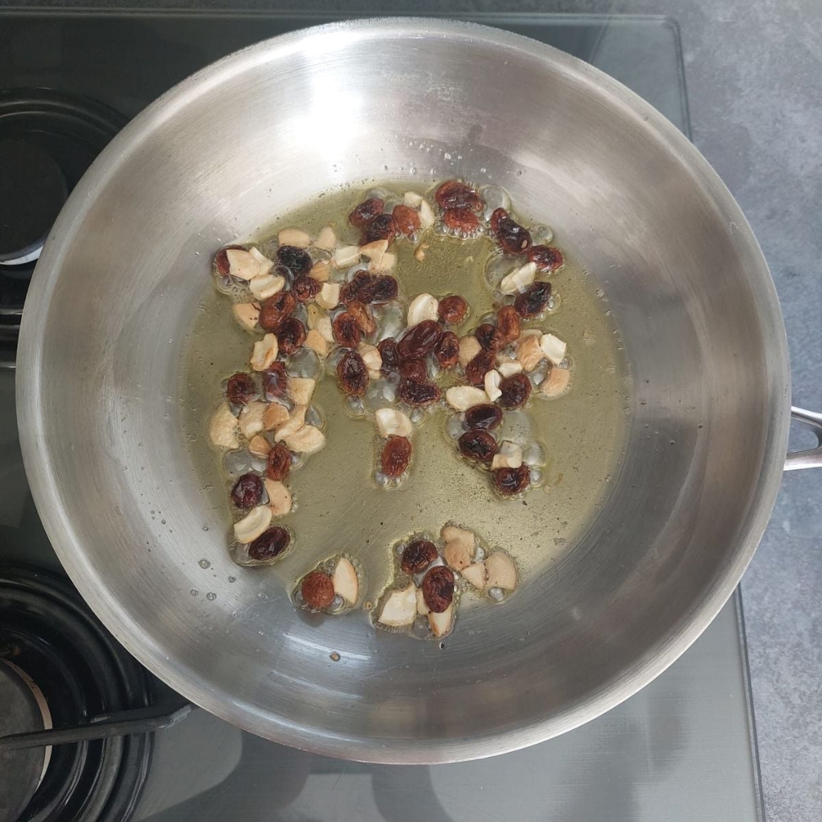 frying cashews and raisins in a wide steel pan.