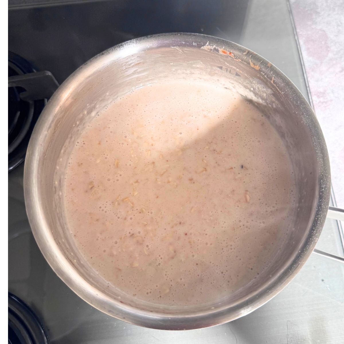 steel pot of oatmeal porridge on stovetop.