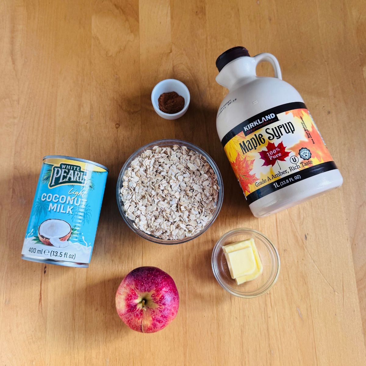 ingredients to cook apple cinnamon oatmeal porridge placed on wooden table.