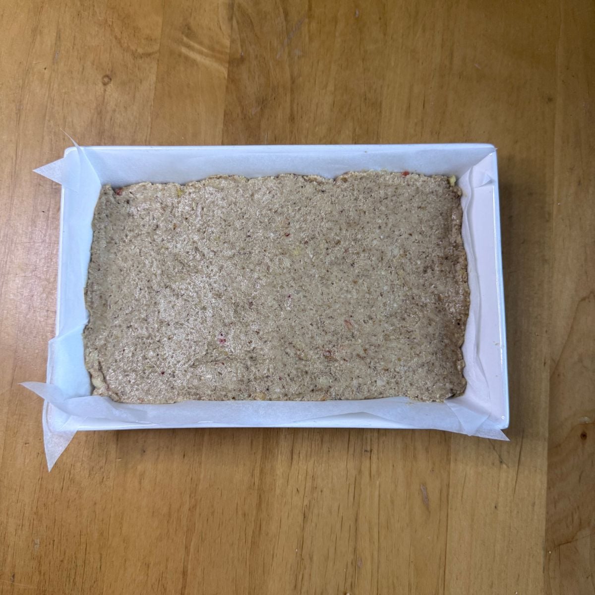 apple oat bar mixture in a baking dish ready to be baked placed on wooden table.