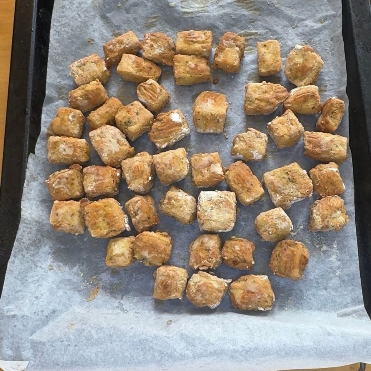 baked gram flour garlic herb tofu cubes on lined baking sheet.