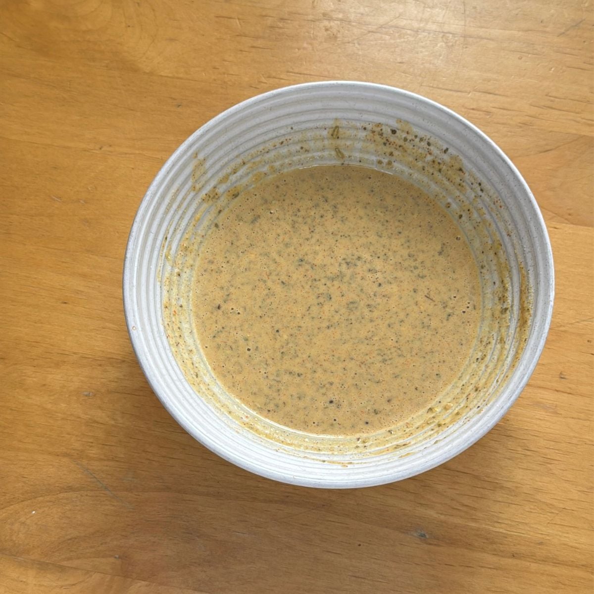 white bowl with gram flour batter placed on wooden table.