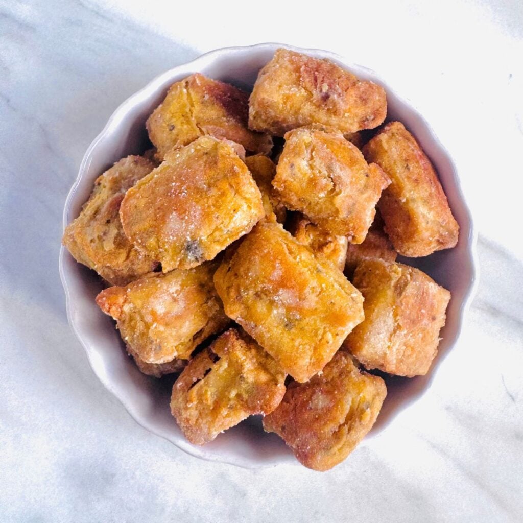 white bowl of baked gram flour garlic herb coated tofu
