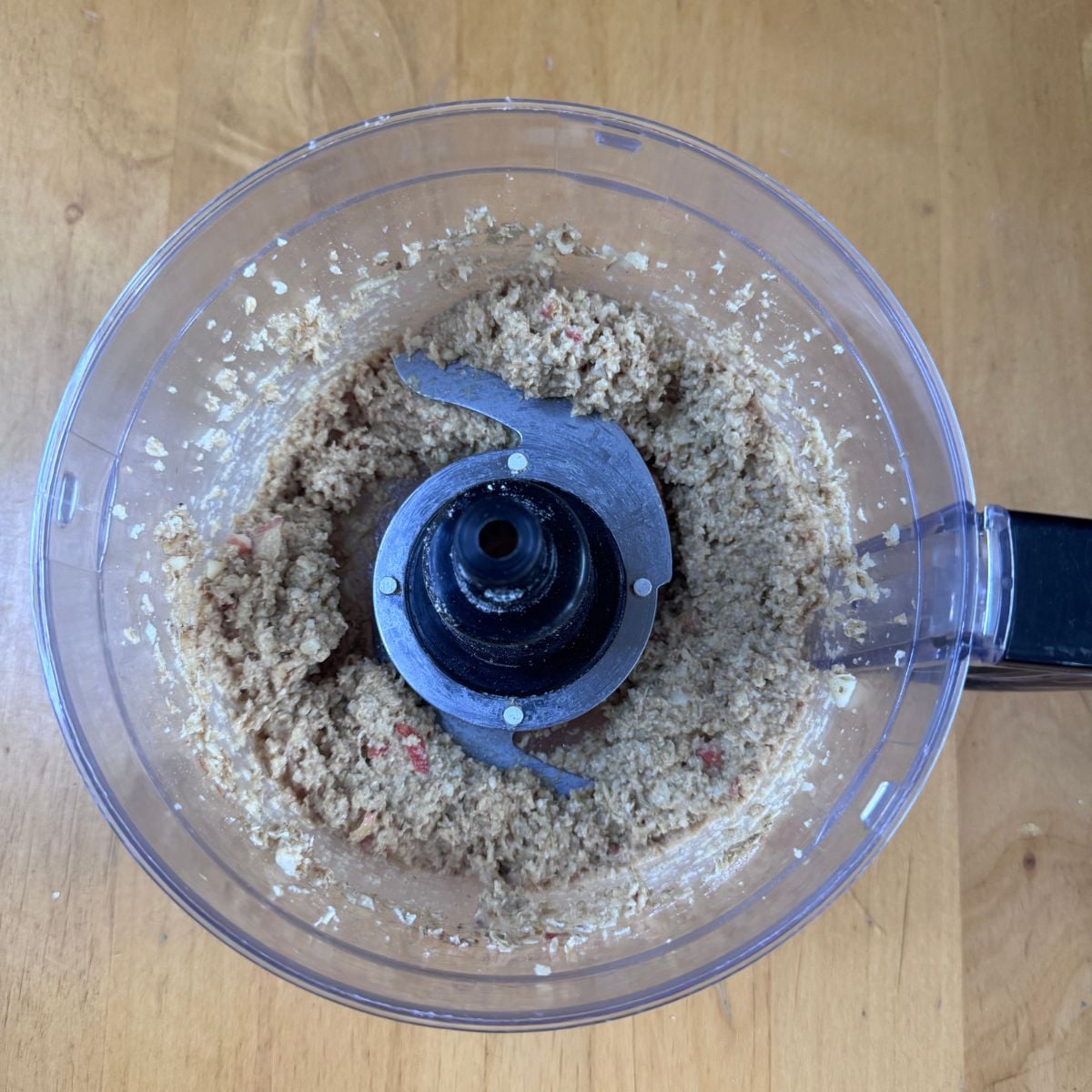 blender jar with apple oat bar mixture placed on wooden table.
