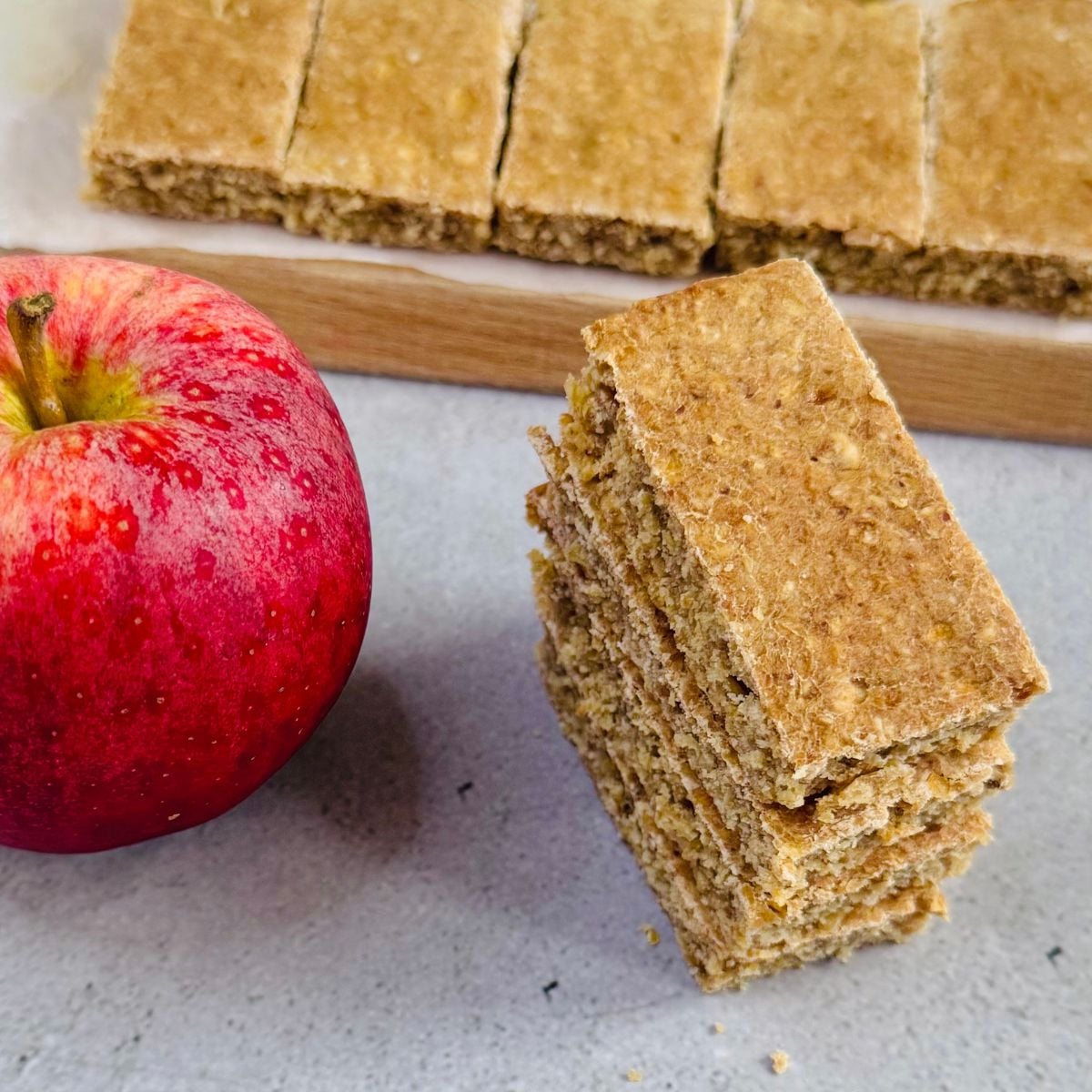 stack of apple oat bars placed on granite along with an apple.